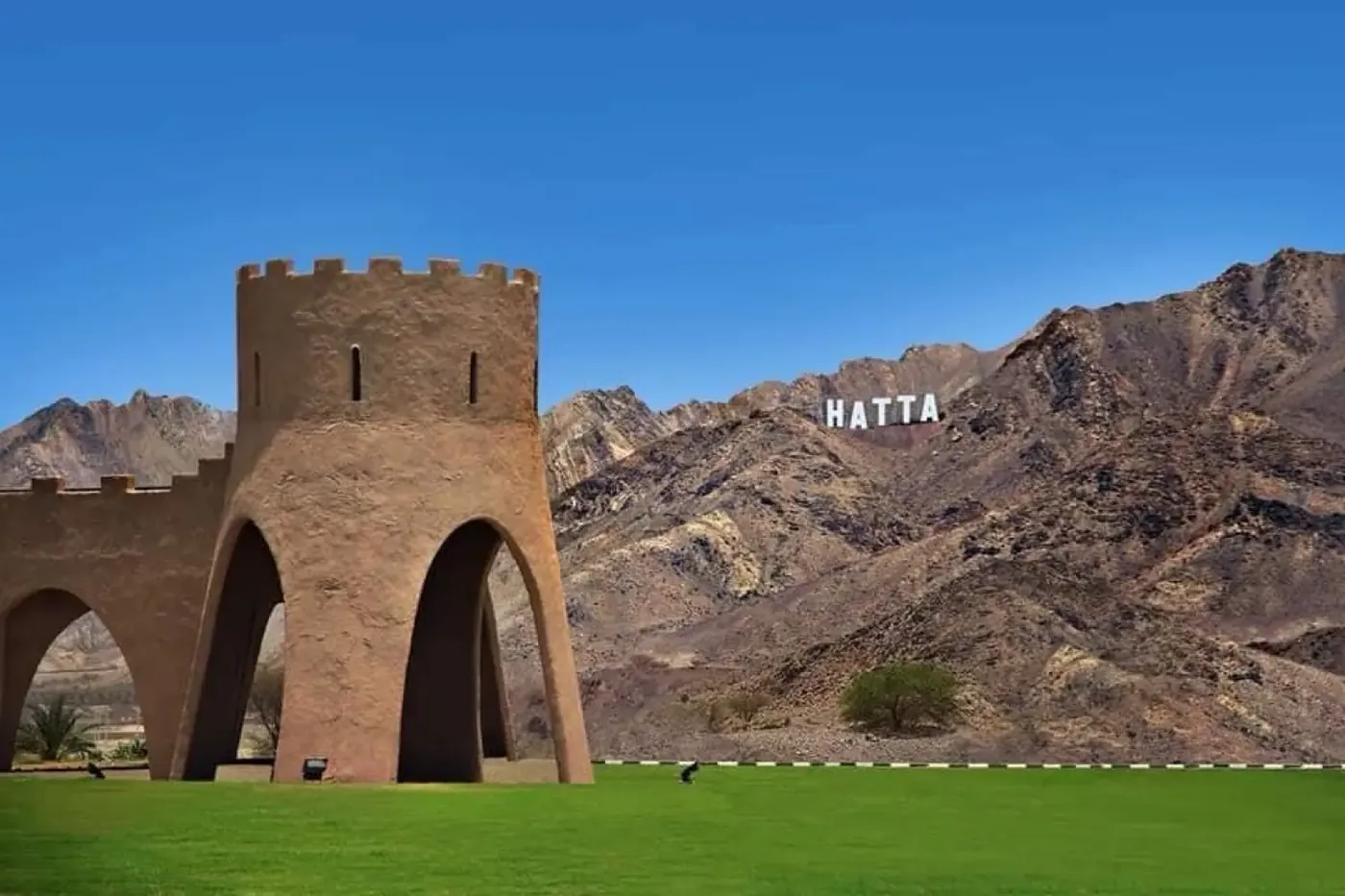Hatta Heritage Village and HATTA sign on mountain - classic Emirati fort