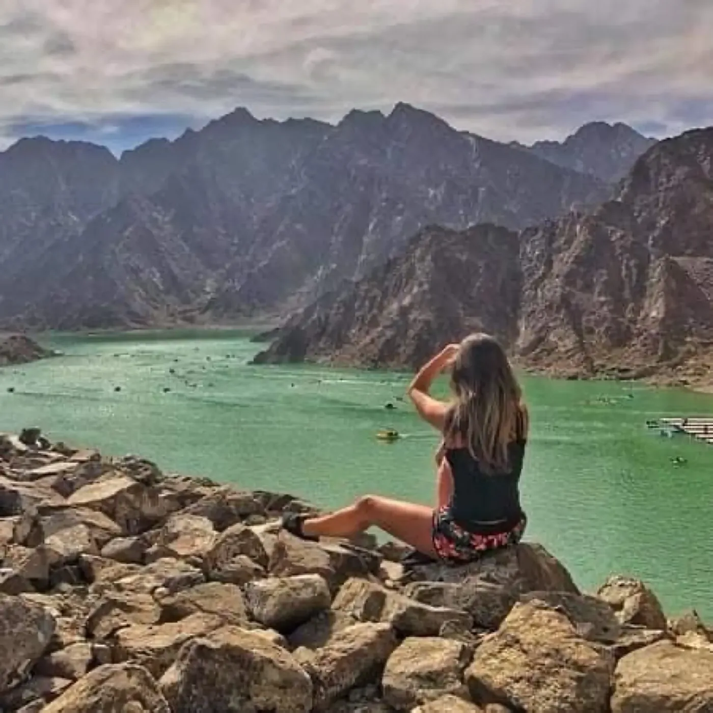 Girl sitting at Hatta Dam rocks enjoying mountain lake view